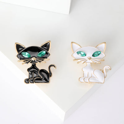 Black and white enamel cat brooches with green eyes side by side
