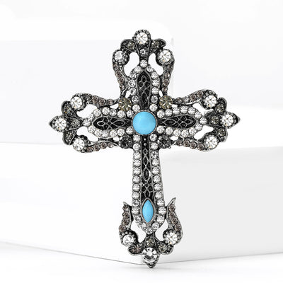 Front view of antique tone cross brooch with turquoise blue cabochons
