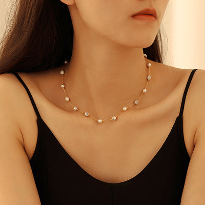 Model wearing gold station necklace with white pearls and stones