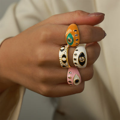 Hand wearing multiple colorful enamel evil eye open rings