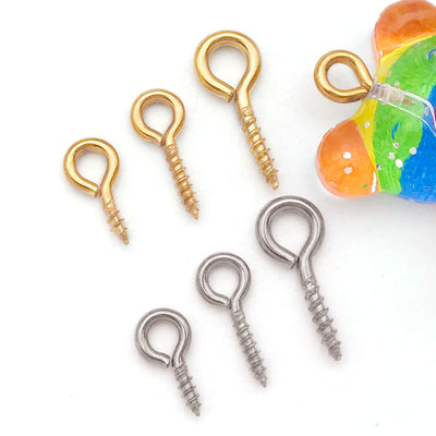 Gold-tone screw eye jewelry findings arranged on a light background