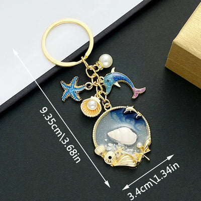 Front product photo of blue dolphin starfish shell and faux pearl ocean charm keychain showing the pictured design arran