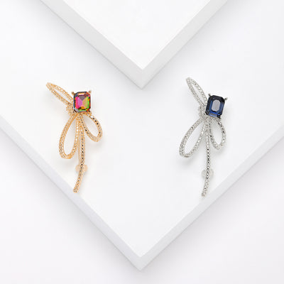 Gold multicolor and silver navy rhinestone bow brooches on white stepped blocks