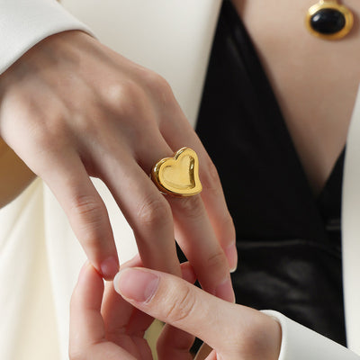 Gold chunky heart signet ring worn on middle finger