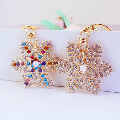 Two gold-tone snowflake keychains display clear and multicolor rhinestone designs.