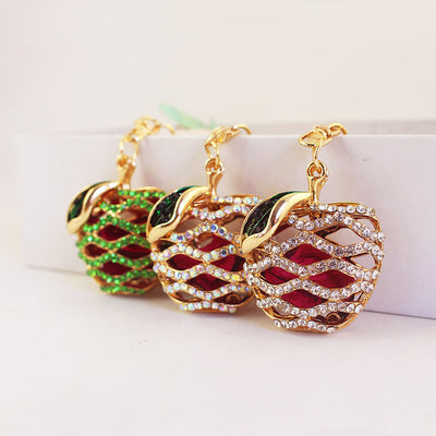 Three apple keychains show clear, iridescent, and green wavy rhinestone rows.