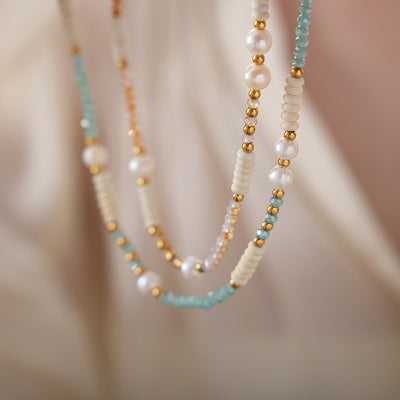 Close-up of layered pearl and colored bead necklaces on fabric