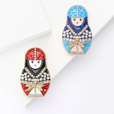 Front view of jeweled nesting doll brooch with pearl details decorative metal pin