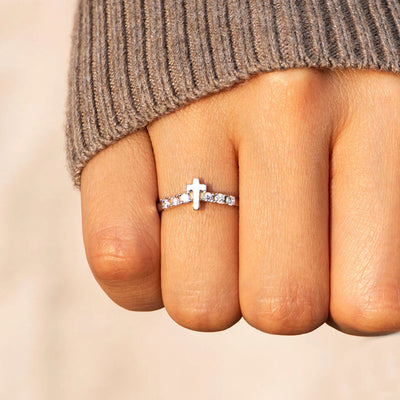 Cross CZ thin band ring on a closed fist with knit sweater cuff