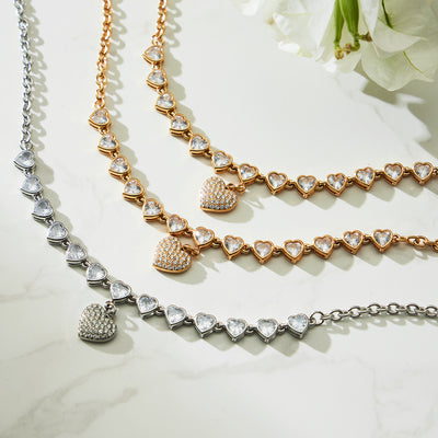 Gold and steel heart zircon station necklaces with pave drops flat lay