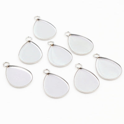 Overview of silver tone teardrop cabochon pendant trays in two sizes arranged on white