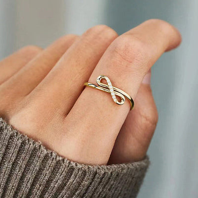Gold infinity line pave clear stone ring worn on finger with knit cuff