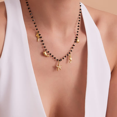 Black crystal ocean charm necklace worn on white dress