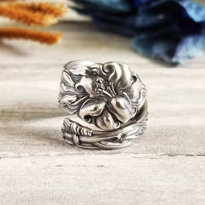 Antique silver embossed hibiscus open wrap ring on light wood