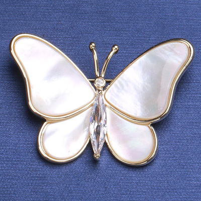 Front view of white shell-effect butterfly brooch with clear crystal body against a white background.