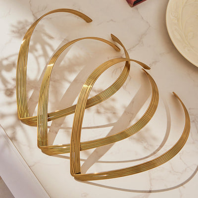 Three gold ribbed V open collar chokers stacked on marble