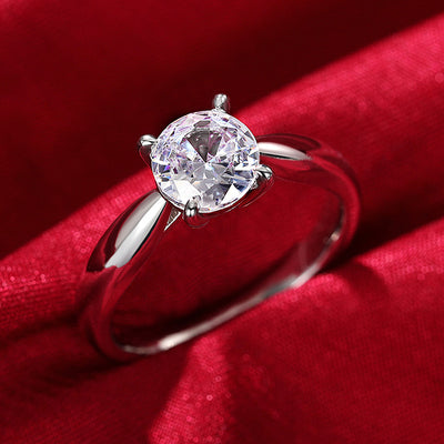 Silver round clear CZ solitaire ring on red satin fabric