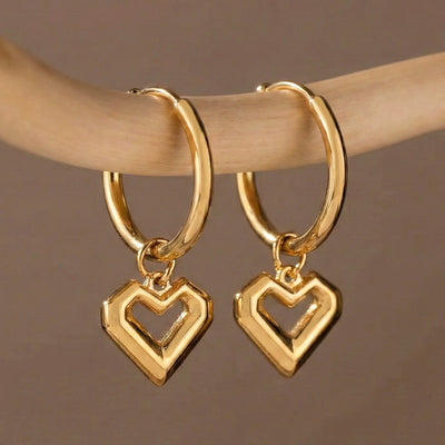 Gold open heart drop huggie hoop earrings hanging on finger