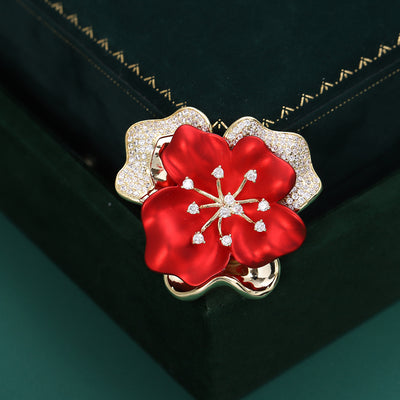 layered red flower brooch with scalloped clear-crystal outer petals worn on a blazer lapel.