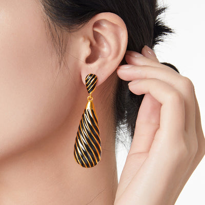 Model wearing black and gold striped teardrop dangle earring