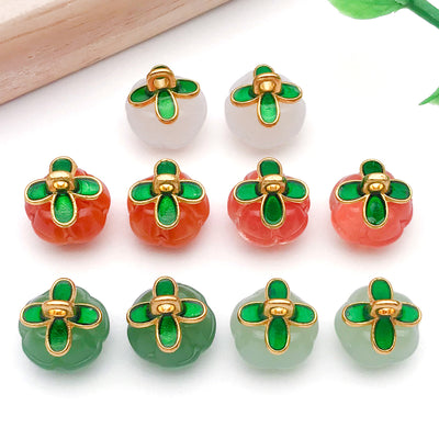 Green four-leaf clover and pumpkin charms arranged on a light background
