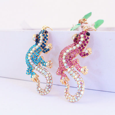 Pink and blue rhinestone lizard charms displayed side by side on a white surface.