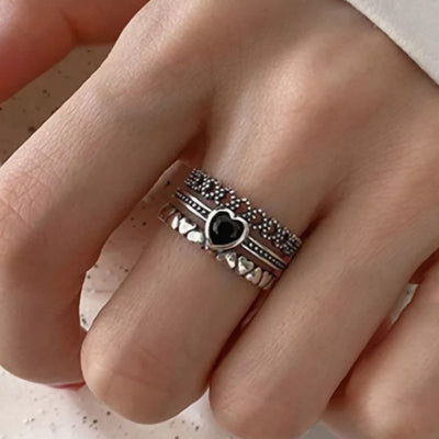 Silver multi band black heart ring worn on finger close view