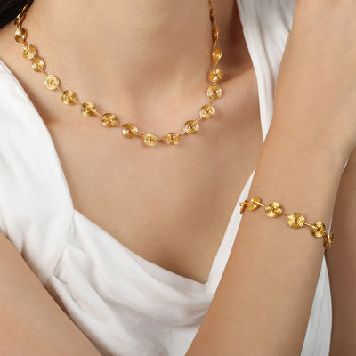 Model wearing gold spiral disc necklace and matching bracelet