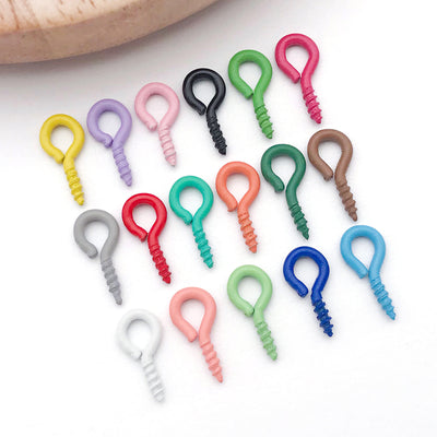 Colorful screw eye jewelry findings arranged on a light background