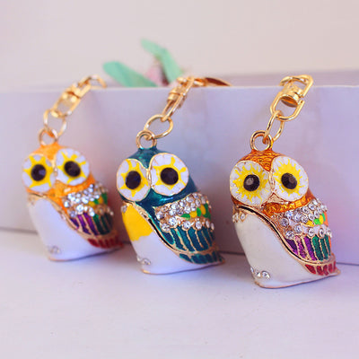 Three colorful owl keychains in gold, blue, and yellow colorways are displayed together.