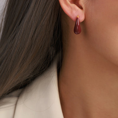 Wine red teardrop enamel stud earring worn on ear