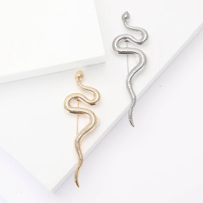 Gold and silver scale snake brooches on white blocks