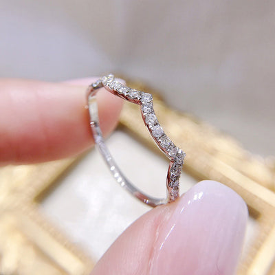 Silver wavy chevron pave band ring held between fingers side profile