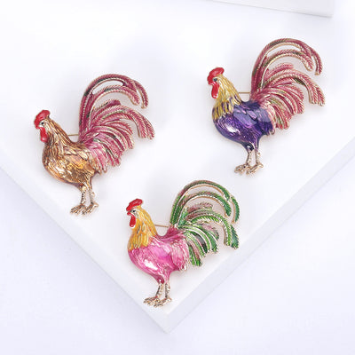 Brown Rooster, Pink Rooster, Purple Rooster brooch styles arranged on a light display