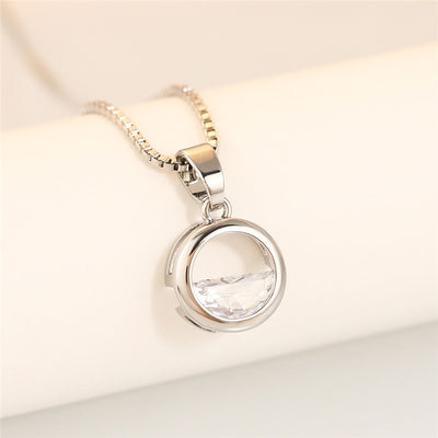 Silver circle half clear stone pendant on box chain over cream roll