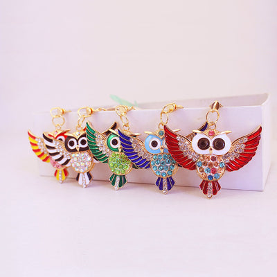 Five colorful winged owl keychains with faceted stones displayed in a row.