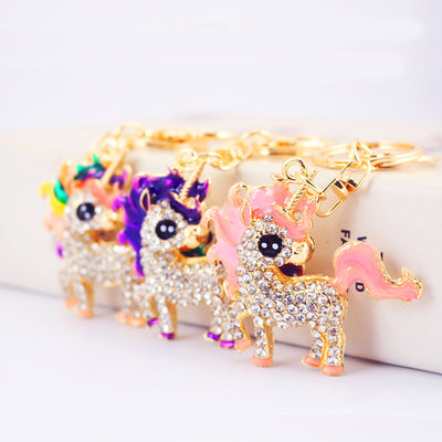 Three gold-tone unicorn keychains with clear rhinestones and pink, purple, and multicolor accents.