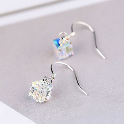 Silver iridescent cube crystal drops on gray surface