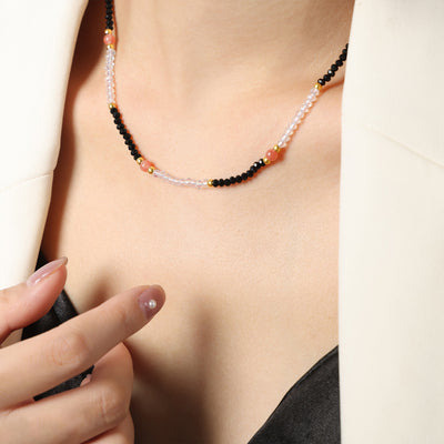 Black clear and pink beaded choker worn on collarbone with cream blazer