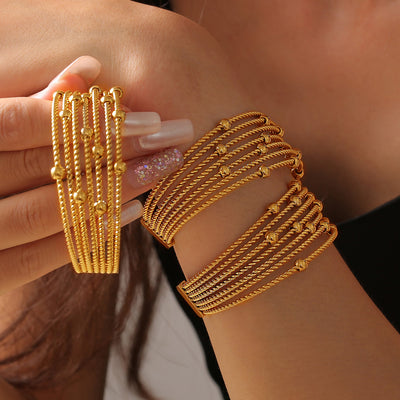 Gold multi-strand twisted rope bead cuff worn and held by model