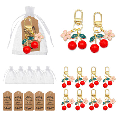 A packaged cherry keychain appears beside loose keychains, white organza bags, and brown thank-you tags.