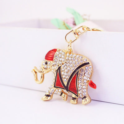 Red-accented rhinestone elephant keychain rests against a white display ledge.