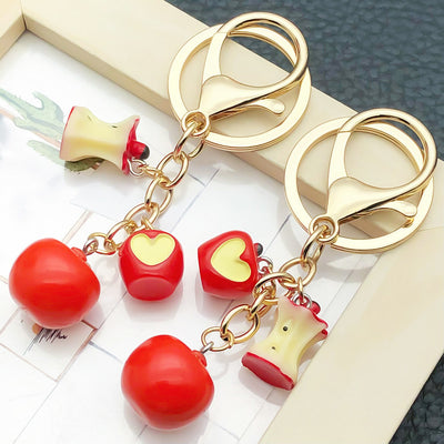Front display of red apple trio keychain with whole cut and core charms with visible colors and attached hardware