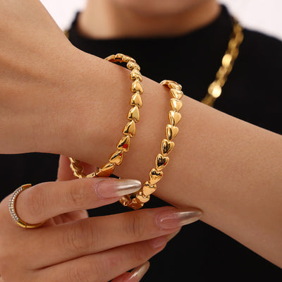 Model wearing two gold solid heart link clasp bracelets stacked
