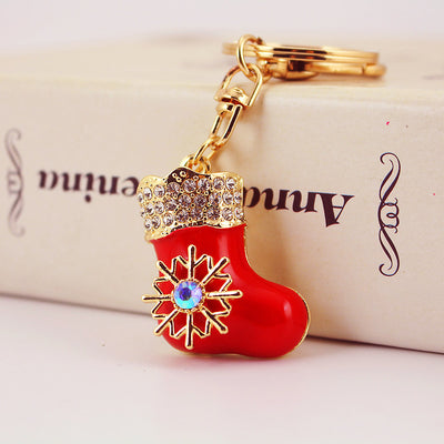 Close-up of a red stocking charm keychain beside a cream box.