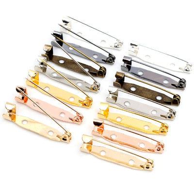 Front overview of bar pin brooch backs with attachment holes in mixed tones arranged on a light background