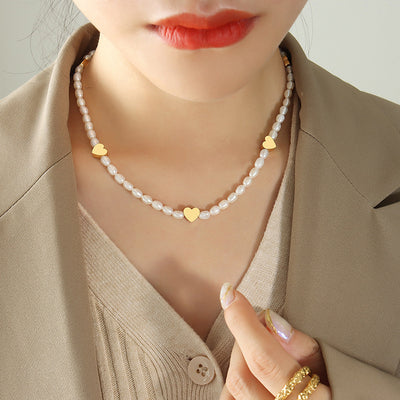 Model wearing white pearl necklace with three gold heart plates
