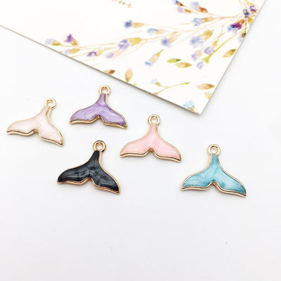 Colorful mermaid tail and mermaid charms arranged on a light background