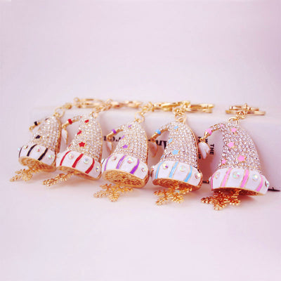 Five gold-tone Christmas hat keychains in black, red, purple, blue, and pink are arranged side by side.