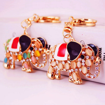 Two gold-tone elephant keychains display pale and multicolor oval inlay designs.